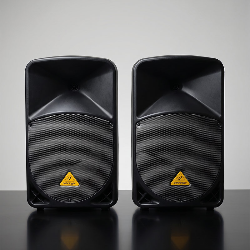 Pair of Behringer Eurolive B112D 1000W 12-inch powered PA speakers mounted for rehearsal monitoring.
